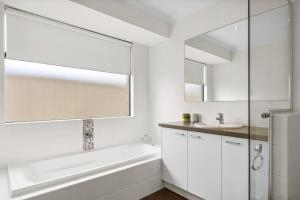 a white bathroom with a tub and a sink at The Dunsborough Drift Family Holiday Home in Dunsborough +15 photos