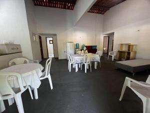 a room with white tables and chairs and a bed at Toca do coelho in Aquiraz