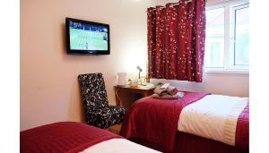 a room with two beds and a tv on the wall at Number Nine Accommodation in Downpatrick