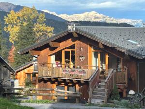 um chalé de madeira com uma varanda e montanhas ao fundo em Charmant 4 pièces avec balcons, proche Méribel - FR-1-180-640 em Les Allues