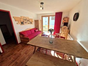 a living room with a table and a red couch at Appartement cosy 3 pièces, 6 pers à 100m des pistes, balcon sud, casier à skis - FR-1-265-372 in Modane