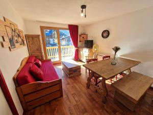 a living room with a red couch and a table at Appartement cosy 3 pièces, 6 pers à 100m des pistes, balcon sud, casier à skis - FR-1-265-372 in Modane