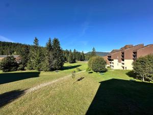 韦尔科尔地区科尔朗松Studio 30m² au pied des pistes à Corrençon-en-Vercors - FR-1-515-220的草场,有树木和建筑