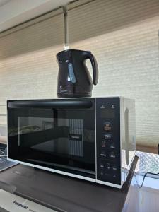 a microwave with a coffee pot on top of it at YOYOGi STAY in Tokyo