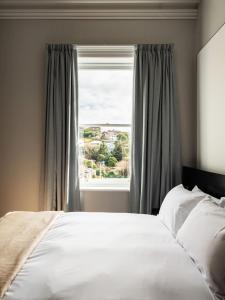 a bedroom with a white bed and a window at The Macquarie in Hobart