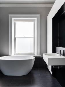 a bathroom with a tub and a sink and a window at The Macquarie in Hobart +15 photos
