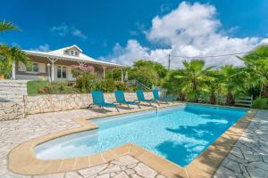 a swimming pool with chairs and a house at Villa Ayiana, magnifique villa avec piscine in Sainte-Anne