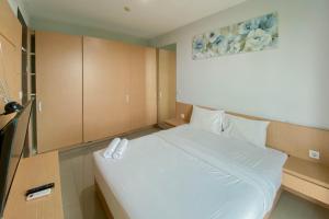 a bedroom with a large white bed in it at Best Deal and Comfort 1BR at Citralake Suites Apartment By Travelio in Jakarta +12 photos