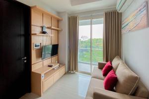 a living room with a couch and a tv and a window at Best Deal and Comfort 1BR at Citralake Suites Apartment By Travelio in Jakarta