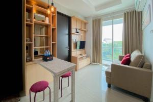 a living room with a table and a couch at Best Deal and Comfort 1BR at Citralake Suites Apartment By Travelio in Jakarta