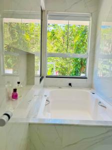 a white bathroom with a tub and a window at Casa com banheira in Governador Celso Ramos +21 photos