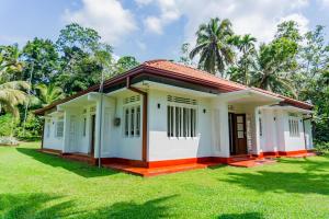 une maison avec une pelouse verte devant dans l'établissement Red Araliya Villa Weligama, à Weligama