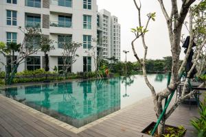 a swimming pool in front of a building at Best Deal and Comfort 1BR at Citralake Suites Apartment By Travelio in Jakarta