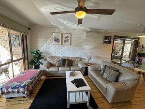 a living room with couches and a ceiling fan at Church St in Bright