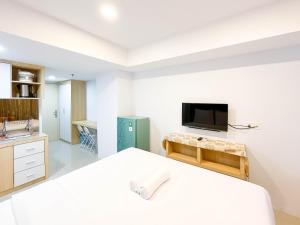 メダンにあるModern Look Studio at De Prima Apartment By Travelioの白いベッドと薄型テレビのある寝室