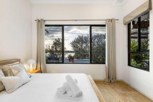une chambre avec un lit blanc et une grande fenêtre dans l'établissement Currumbin Beachside Retreat, à Gold Coast