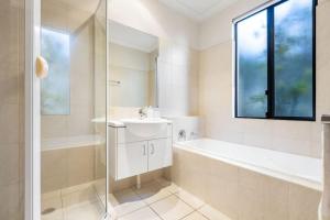 une salle de bain blanche avec un lavabo et une baignoire dans l'établissement Currumbin Beachside Retreat, à Gold Coast 25 autres photos