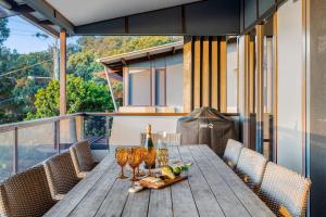 - une table en bois avec des verres à vin sur le balcon dans l'établissement Currumbin Beachside Retreat, à Gold Coast