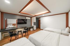 a hotel room with two beds and a flat screen tv at Hotel Tate V in Suwon