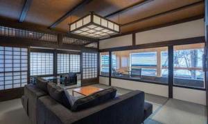 a living room with a large couch and windows at Ryugon in Minami Uonuma