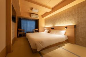 Un dormitorio con una gran cama blanca en una habitación. en WELLSTAY Shinsekai Wakyo, en Osaka