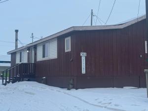 a red building with a sign on it in the snow at Kings Studio Apartment B in Nome