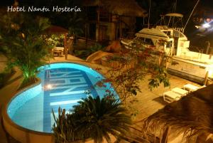een groot zwembad naast een boot in de nacht bij Hotel Nantu Hostería in Puerto López