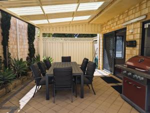 a patio with a table and chairs and a grill at Rockingham Beach Townhouse in Rockingham