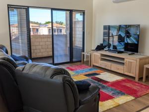 a living room with a couch and a flat screen tv at Rockingham Beach Townhouse in Rockingham