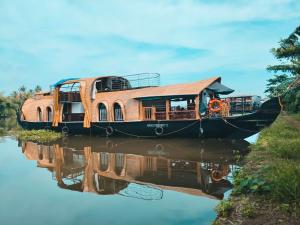 阿勒皮Kalappura Houseboats & Tours的船屋停靠在水面上