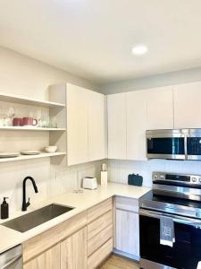 a kitchen with white cabinets and a sink and a stove at Cozy Modern 1 Bedroom Apartment in Davenport +2 photos