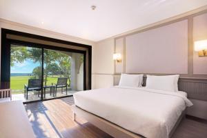 a bedroom with a large bed and a large window at Pinnacle Grand Jomtien Resort and Beach Club in Na Jomtien