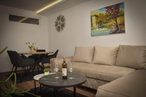 a living room with a couch and a bottle of wine on a table at Apartman PLAN B in Banja Luka
