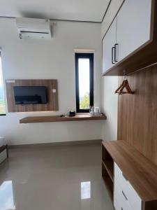 a kitchen with white walls and a tv on the wall at SALU AMAANA Residence Syariah in Wonosobo +31 photos