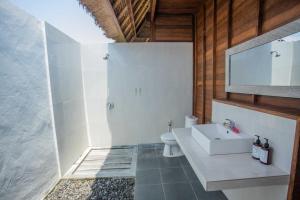 a bathroom with a white sink and a toilet at Lembongan Mantra Huts in Nusa Lembongan +32 photos