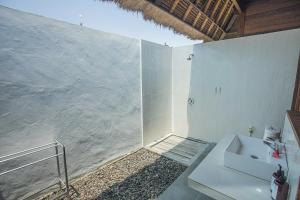 a white bathroom with a sink and a shower at Lembongan Mantra Huts in Nusa Lembongan