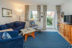 a living room with a blue couch and a tv at Ferienhaus Lobbe - Wohnung 3 in Lobbe