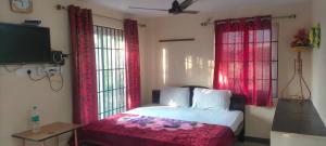 una camera da letto con un letto con tende rosse e una TV di Zeeenu Abode Yercaud by GD a Yercaud