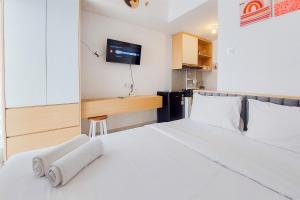 a bedroom with a white bed with a tv on the wall at Minimalist and Strategic Studio at Serpong Garden Apartment By Travelio in Tangerang
