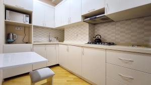 a kitchen with white cabinets and a stool in it at Апартаменты возле метро in Baku +8 photos