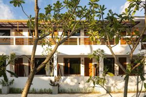 a white building with trees in front of it at Zen Inn Fulhadhoo in Fulhadhoo