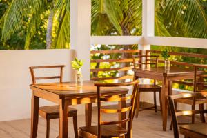 two tables and chairs on a patio with palm trees at Zen Inn Fulhadhoo in Fulhadhoo