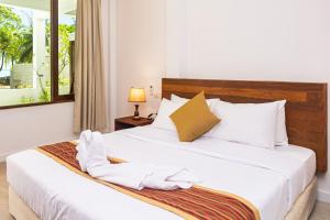 a bedroom with a bed with white sheets and a window at Zen Inn Fulhadhoo in Fulhadhoo