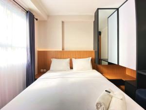 バンドンにあるNice 2BR at Gateway Pasteur Apartment By Travelioのベッドルーム(鏡付きの大きな白いベッド1台付)