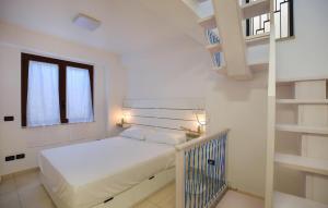 a white bedroom with a bed and a staircase at Casa Morgana in Scilla