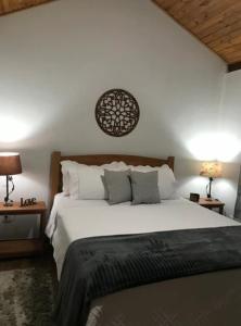 a bedroom with a large white bed with two lamps at Verde Mauá Chales in Visconde De Maua