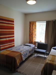 a bedroom with a bed and a chair and a window at OuluHostel AlliMaria in Oulu +4 photos