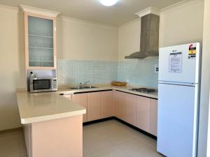 a kitchen with a white refrigerator and a sink at Oh Bouy, Unit 62 Seafront Estate in Jurien Bay