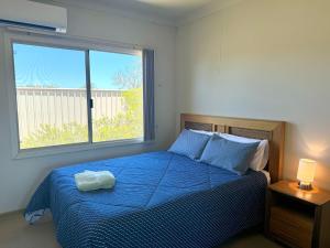 a bedroom with a bed with a blue comforter and a window at Oh Bouy, Unit 62 Seafront Estate in Jurien Bay +13 photos
