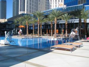 a large swimming pool with palm trees in a city at Suites at Elara Las Vegas Center Strip-No Resort Fees in Las Vegas